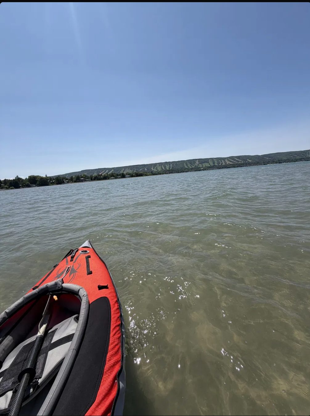 A kayak on the calm open water of Georgian Bay, with the Blue Mountain escarpment across the bay