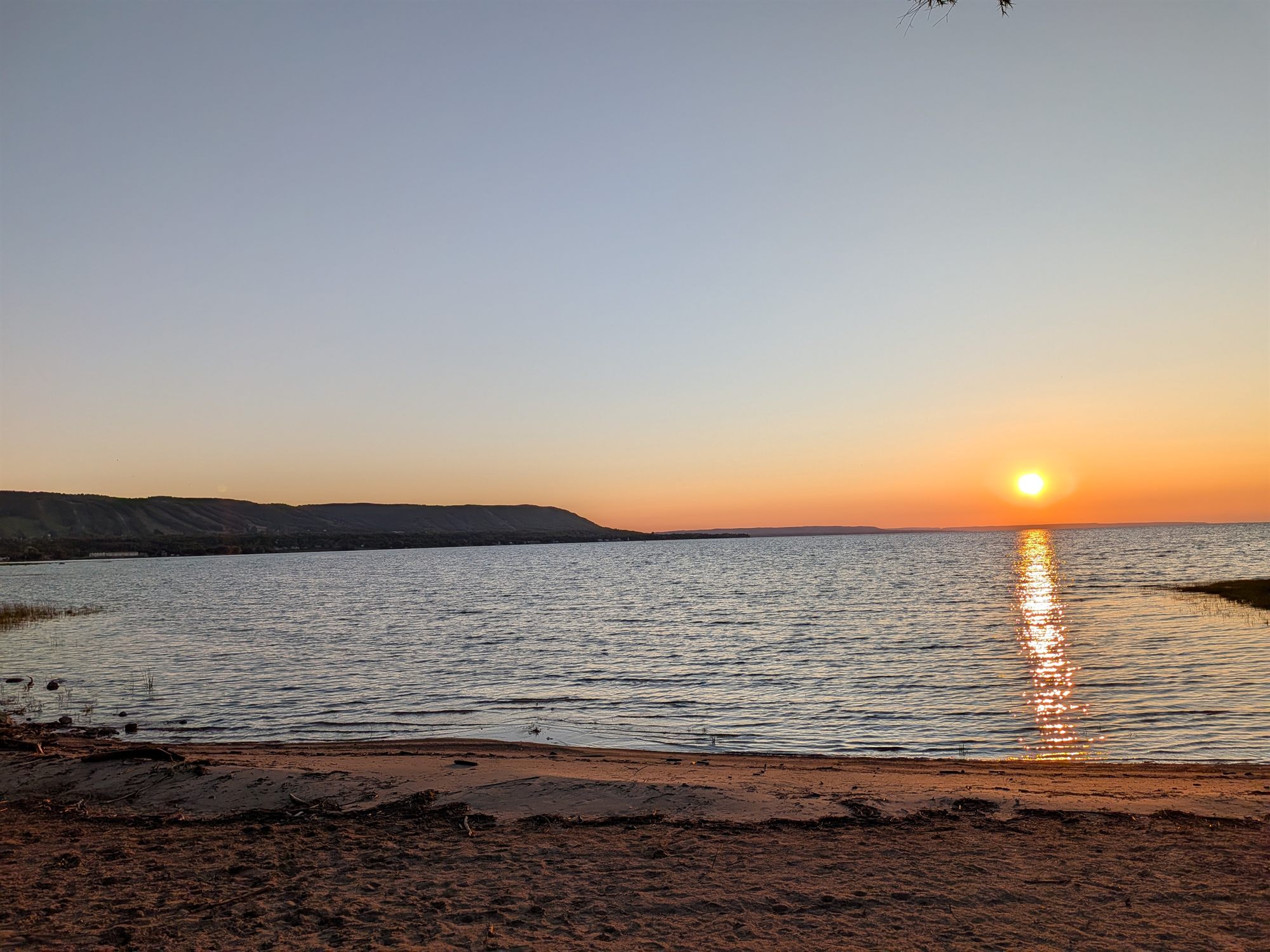 Sunset over the private Georgian Bay beach, where fire pits and BBQ areas are set up on the sand