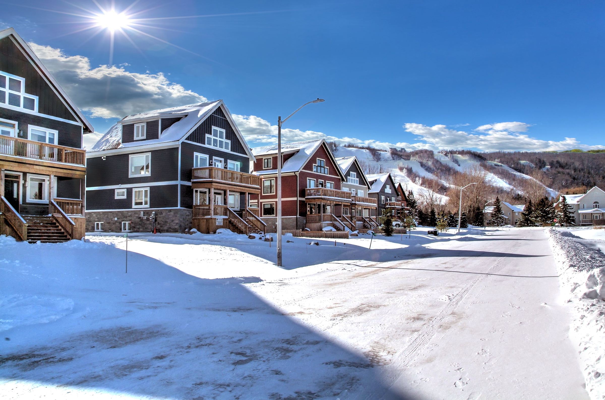 The three Tyrolean luxury chalets in the snow with the Blue Mountain ski runs right behind them